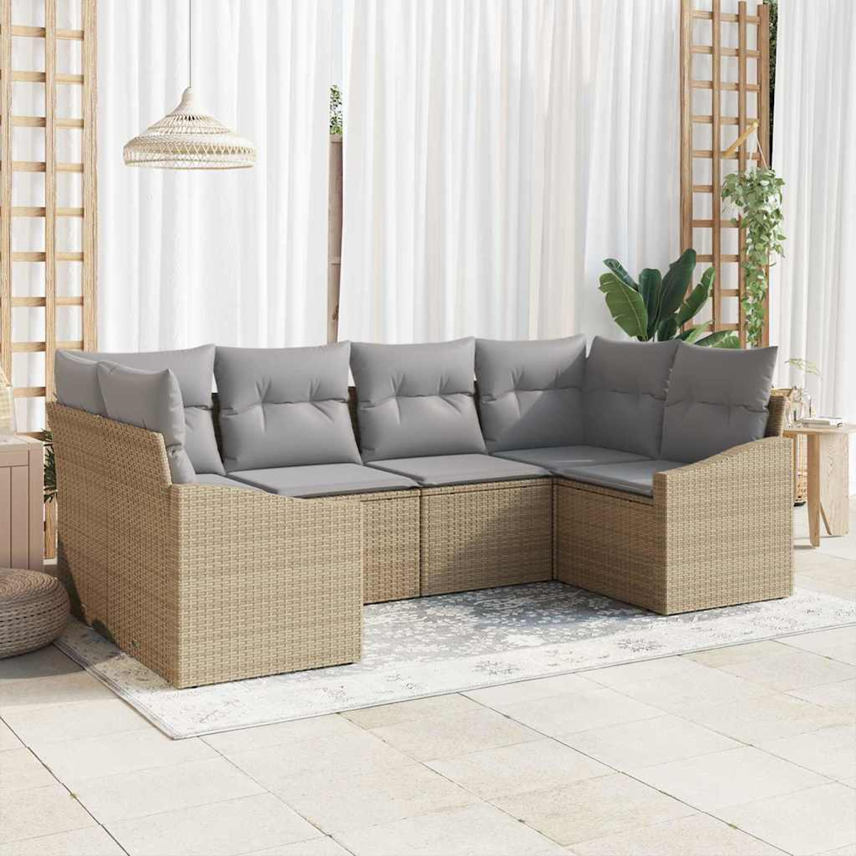 Ein Ecksofa für draußen mit grauen Kissen. Beige Korbflechtrahmen und ein heller Teppich auf einer Terrasse. Weiße Vorhänge und eine Hängelampe.