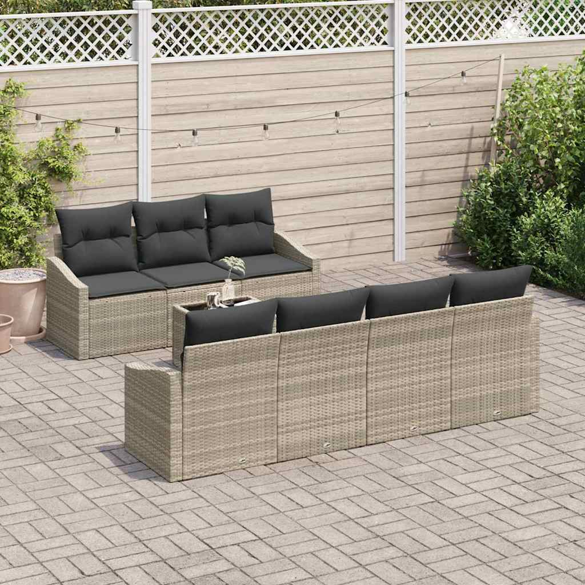 Zwei Korbs Sofas mit schwarzen Kissen stehen auf einer Terrasse. Im Hintergrund ist ein weißer Zaun. Vor den Sofas steht ein kleiner Tisch.