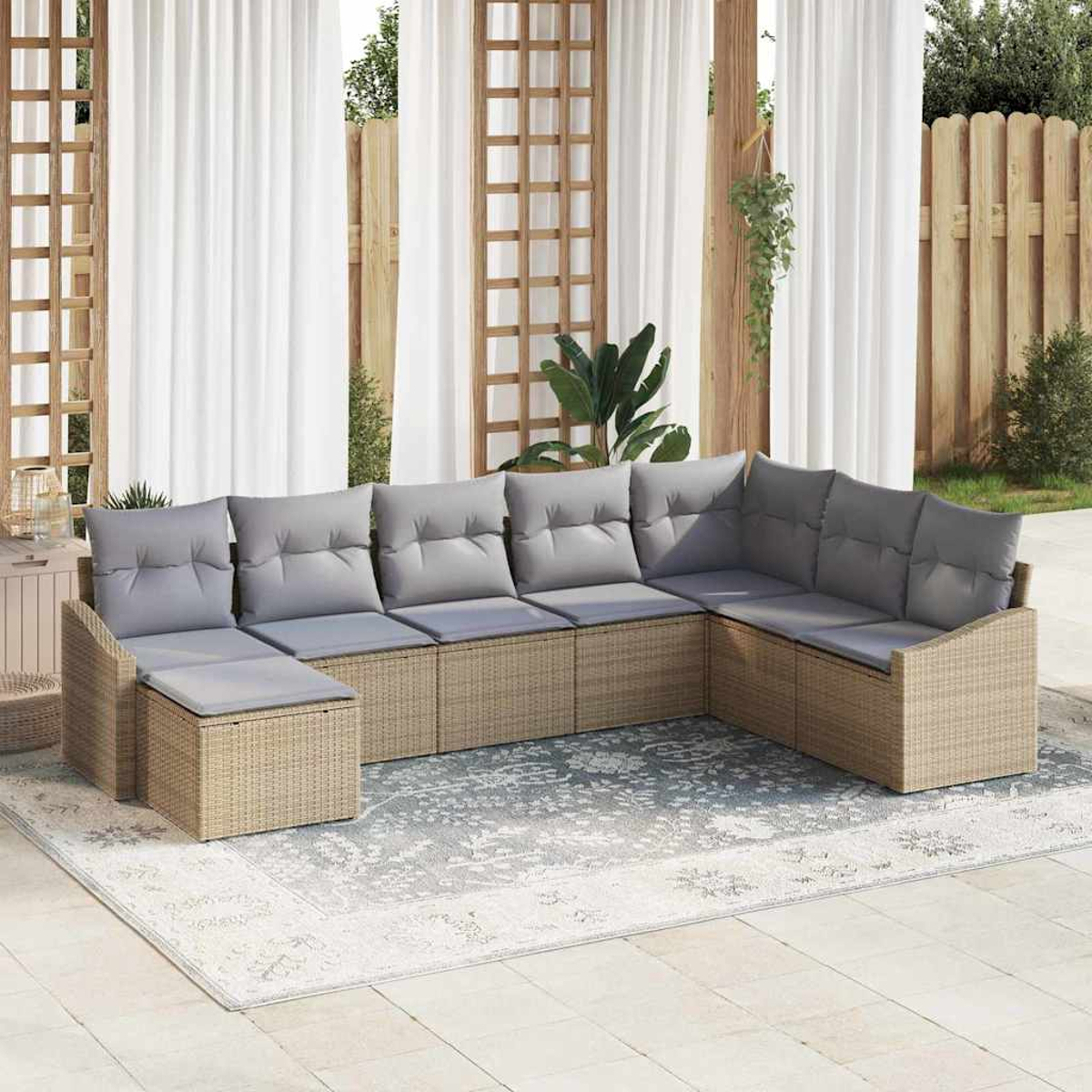 Ein beiges Ecksofa mit grauen Kissen steht auf einem gemusterten Teppich. Weiße Vorhänge und ein Holzzaun sind im Hintergrund.