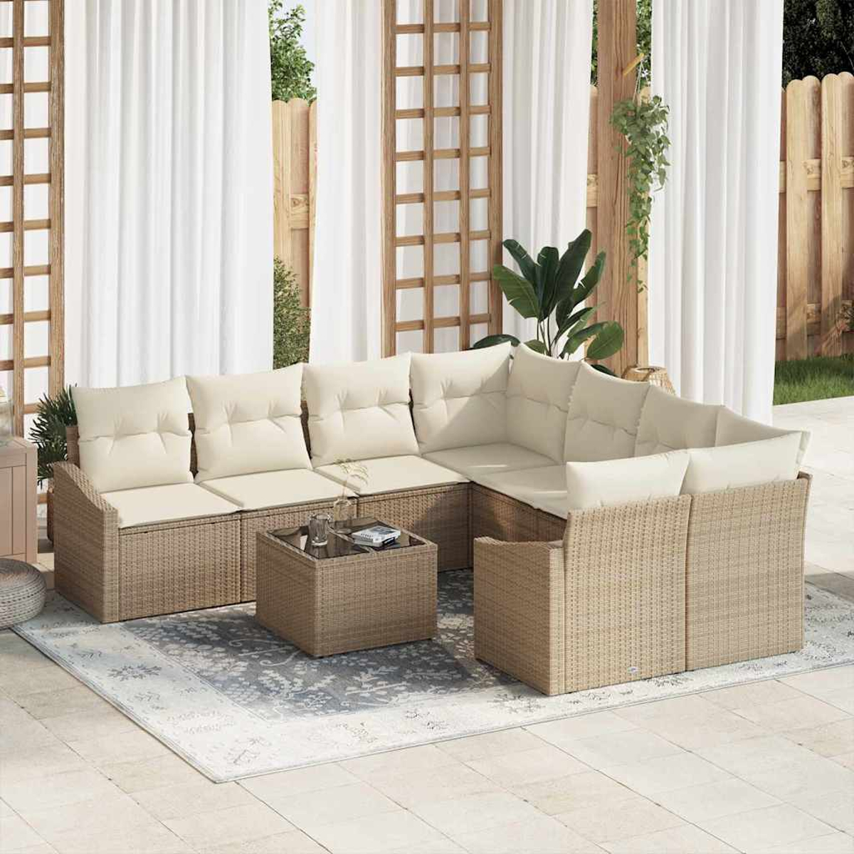 Outdoor-Terrassen-Set mit beigen Kissen. Enthält ein Ecksofa, einen Couchtisch und einen Teppich. Weiße Vorhänge und Holzzaun im Hintergrund.