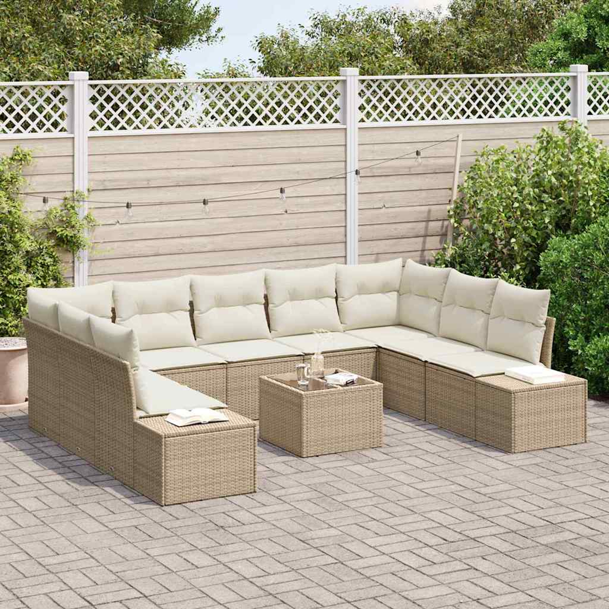 Gartenmöbel-Set. Beige-Wicker-Ecksofa mit cremefarbenen Kissen, Couchtisch und Gitterzaun im Hintergrund.