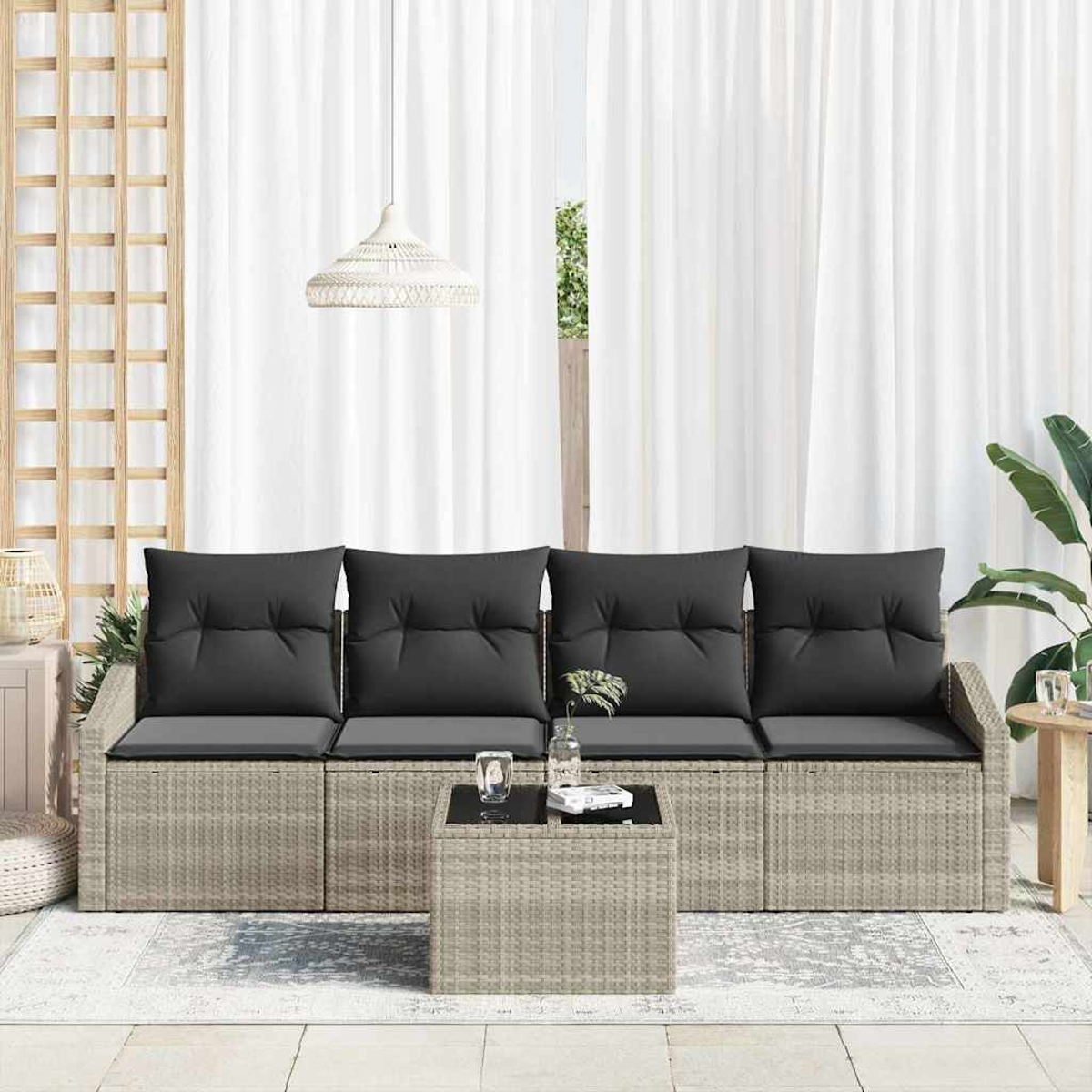 Outdoor-Sitzgruppe mit grauen Kissen. Enthält einen Couchtisch und einen weißen Vorhanghintergrund. Pflanzen und eine Holzkonstruktion sind ebenfalls sichtbar.