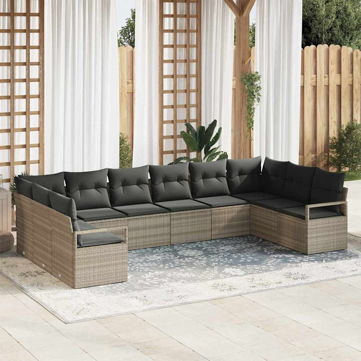 Outdoor-Ecksofa mit grauen Kissen auf einem gemusterten Teppich in einer Terrasse mit Vorhängen und Holzzaun.