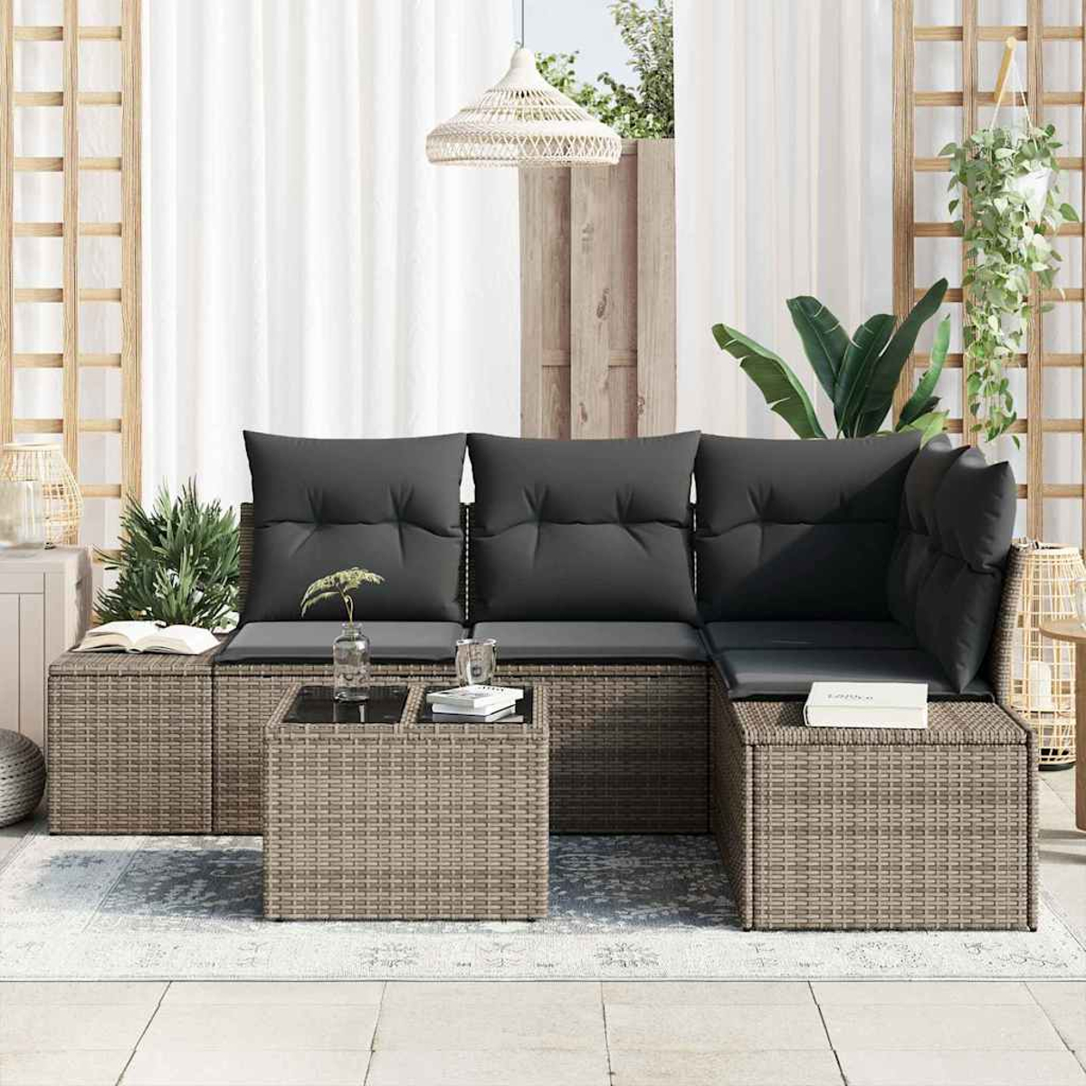 Outdoor-Ecksofa mit grauen Kissen und einem Tisch mit Glasplatte. Pflanzen, weiße Vorhänge und eine Hängelampe im Hintergrund.