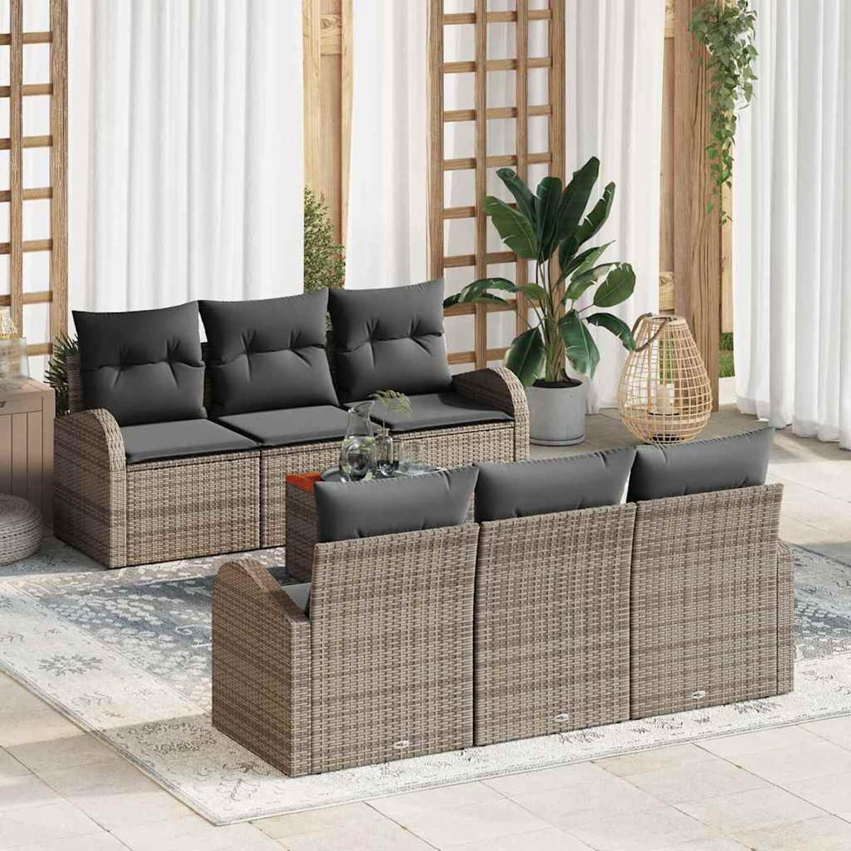 Juego de muebles de patio con cojines grises. Incluye un sofá y un sofá en una alfombra, con plantas y una linterna decorativa.