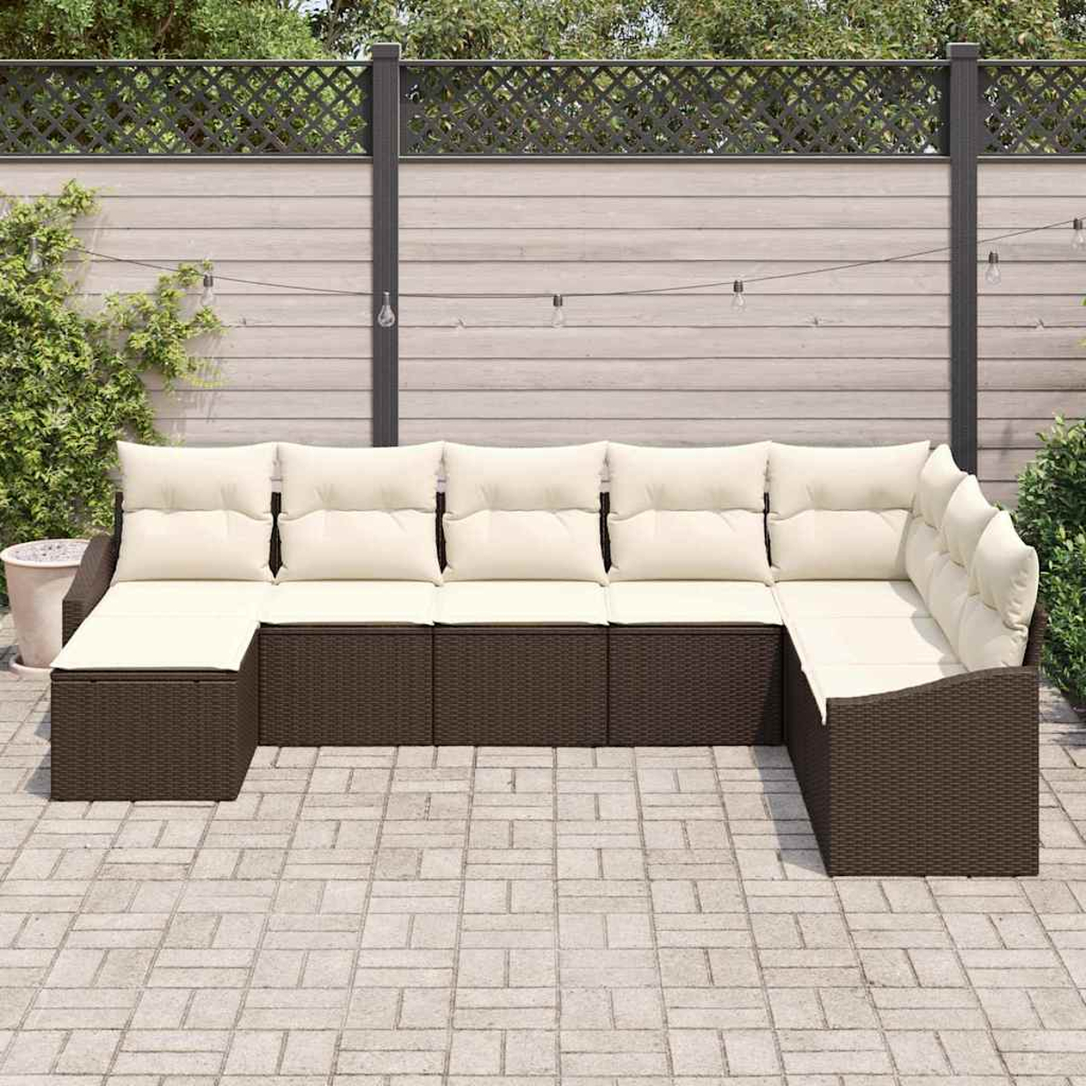 Ein Ecksofa im Freien mit cremefarbenen Kissen und braunem Korbbasish. Es steht auf einer Steinterrasse vor einem Zaun.