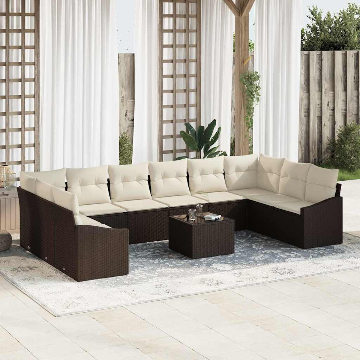 Outdoor-Ecksofa mit cremefarbenen Kissen, brauner Webbasis, auf einem gemusterten Teppich. Weiße Vorhänge und Holzgitter im Hintergrund.