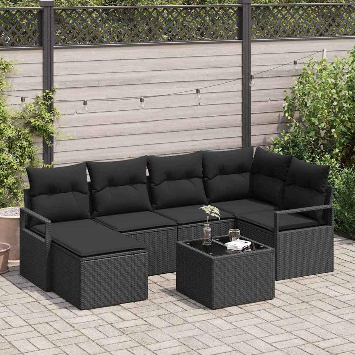 Ein Terrassenset mit schwarzen Kissen und einem kleinen Tisch. Der Hintergrund hat einen Holzzaun, Pflanzen und Lichterketten.