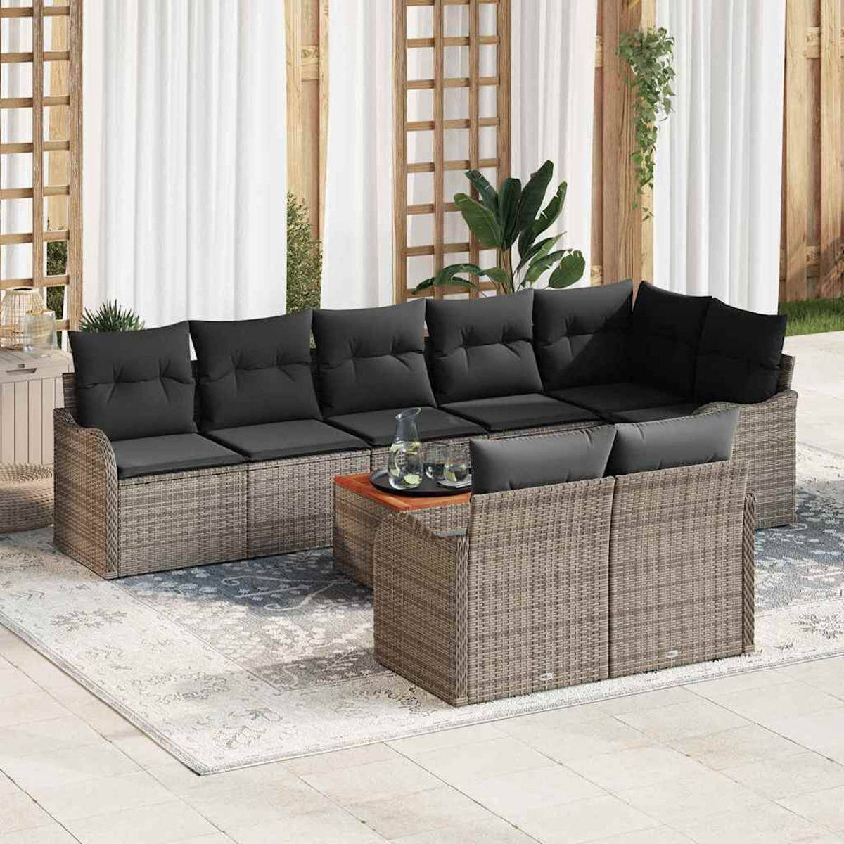 Garten-Terrassenset mit grauen Kissen auf einem gemusterten Teppich. Enthält Sofa, Loveseat und Couchtisch. Hintergrund mit Vorhängen und Pflanzen.