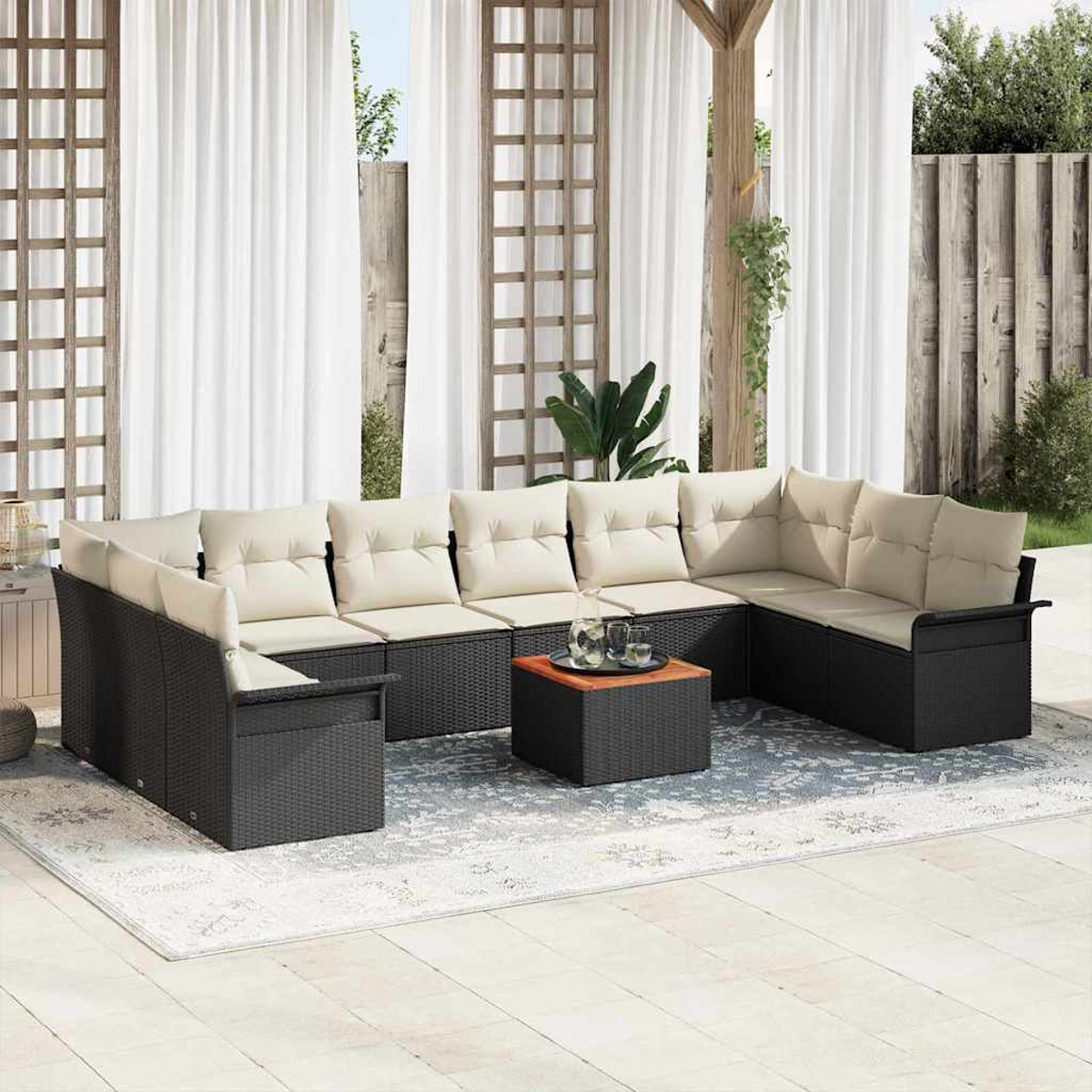 Outdoor-Ecksofa mit beigefarbenen Kissen, auf einem Teppich und einem kleinen Tisch. Weiße Vorhänge und Holzgitter im Hintergrund.