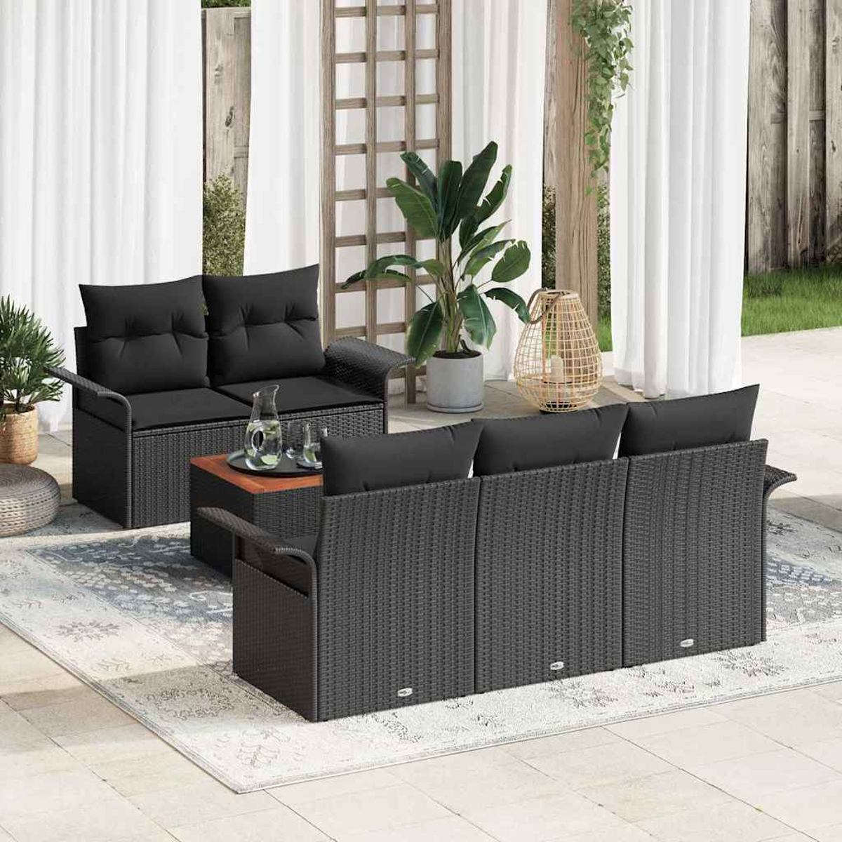 Outdoor-Sitzgruppe mit schwarzem Korbmöbel, darunter ein Liebessessel, ein Sofa und ein Couchtisch auf einer Terrasse mit Pflanzen.