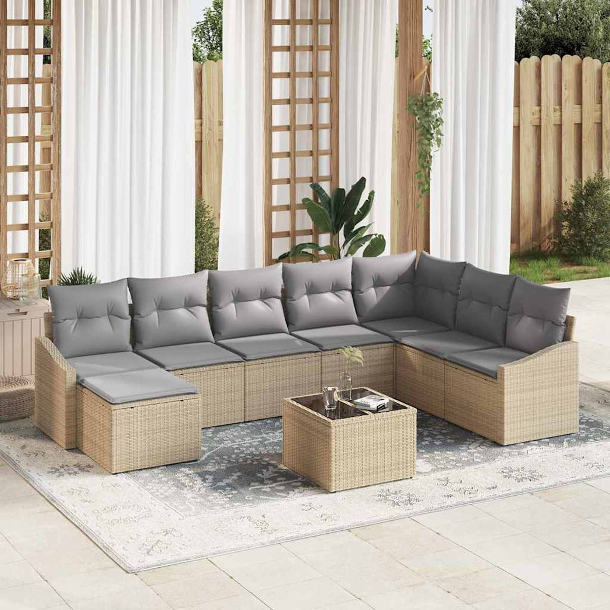 Outdoor-Sitzbereich mit beigem gewebtem Sofa und grauen Kissen. Ein kleiner Tisch und ein Teppich befinden sich vor dem Sofa.