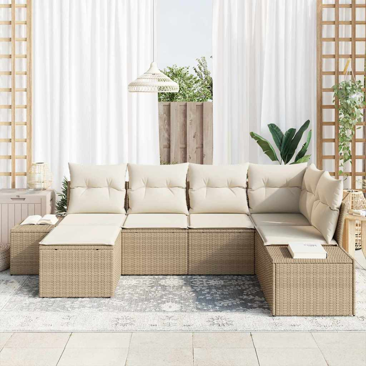 Divano componibile da esterno con cuscini color crema. Base intrecciata beige. Tende bianche, lampada a sospensione, piante e struttura a traliccio sullo sfondo.