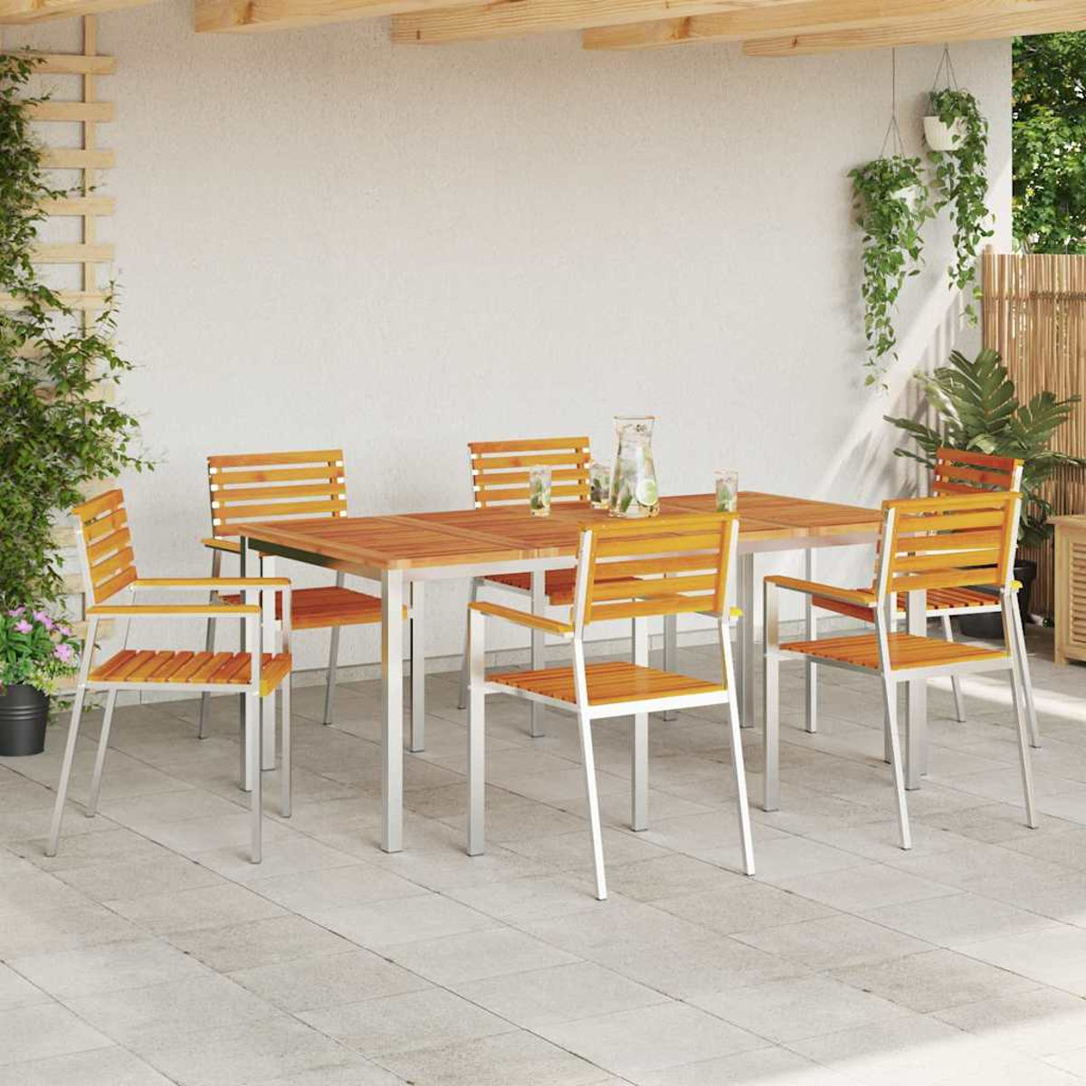 Essgruppe im Freien: Holztisch und Stühle auf einer Terrasse. Pflanzen in Töpfen und hängend. Klarer Wasserkrug.