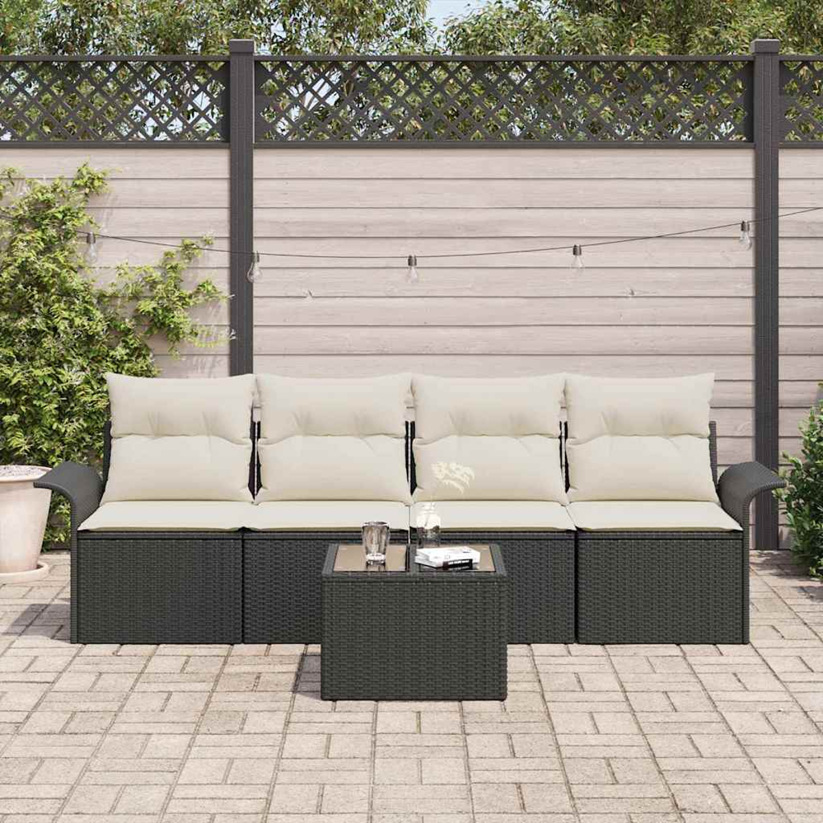 Garten-Terrassenset mit dunkelgrauem Korbsessel, hellen Kissen und einem passenden Couchtisch. Der Hintergrund umfasst einen Zaun.