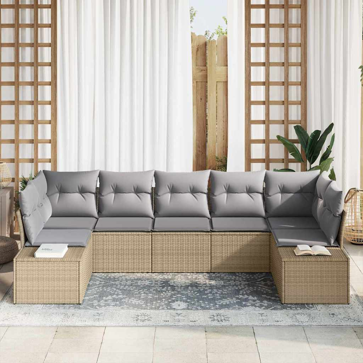 Ein Korbschnittsofa mit grauen Kissen steht auf einem Teppich. Dahinter sind weiße Vorhänge und Holzgitterplatten zu sehen.