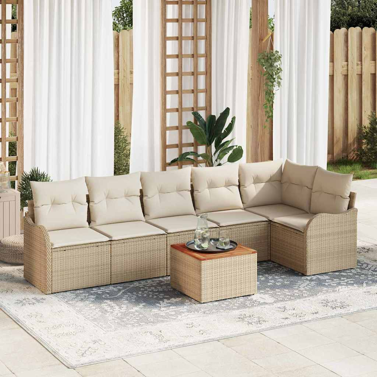 Outdoor-Ecksofa mit beigen Kissen, einem Holztisch und einem Teppich. Weiße Vorhänge und ein Holzzaun sind im Hintergrund.