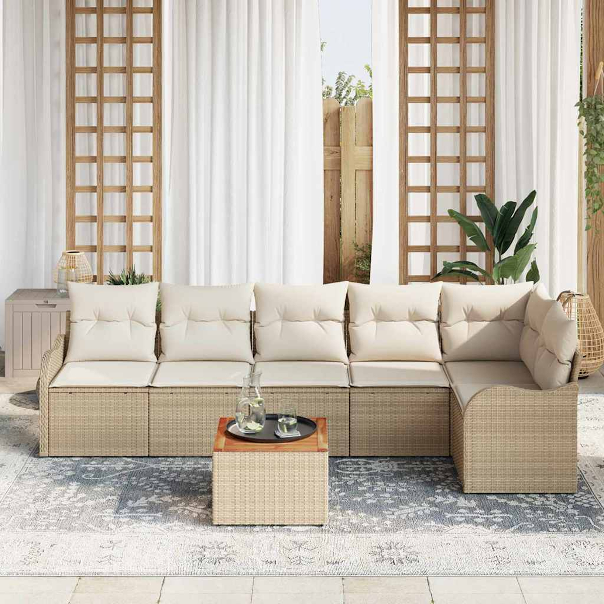 Outdoor-Ecksofa mit beigefarbenen Kissen. Ein kleiner Tisch mit Getränken steht auf einem gemusterten Teppich. Weiße Vorhänge und Holzgitter.