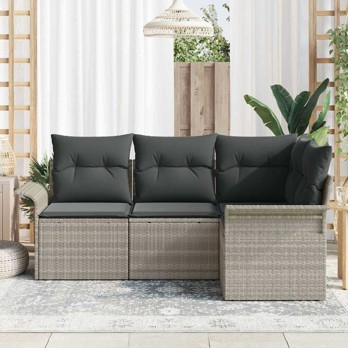 Ein Ecksofa im Freien mit grauen Kissen steht auf einem gemusterten Teppich. Im Hintergrund sind ein weißer Vorhang und ein Holzgitter.