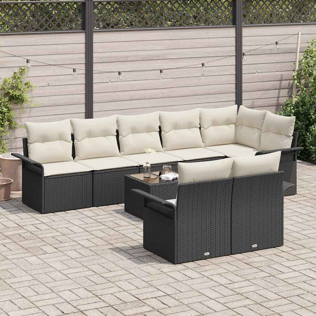 Terrassenset mit schwarzer Korbmöbel, beigen Kissen und einem kleinen Tisch. Ein Holzzaun und Pflanzen sind im Hintergrund.