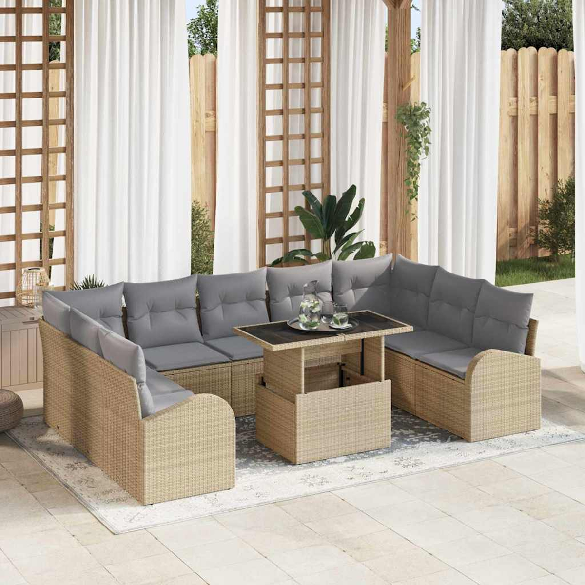 Outdoor-Sitzbereich mit einem beigefarbenen, gewebten Ecksofa, grauen Kissen und einem Tisch. Weiße Vorhänge und Holzzaun im Hintergrund.