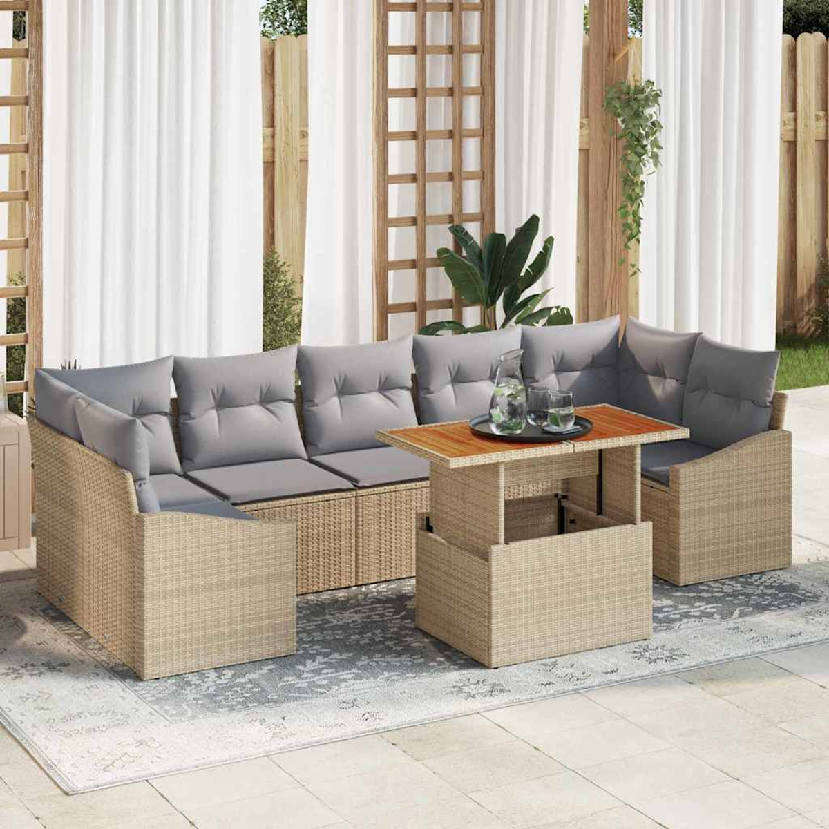 Gartenmöbel-Set aus Korbgeflecht mit grauen Kissen. Ein Tisch mit Holzplatte hat Gläser und einen Krug. Weiße Vorhänge im Hintergrund.