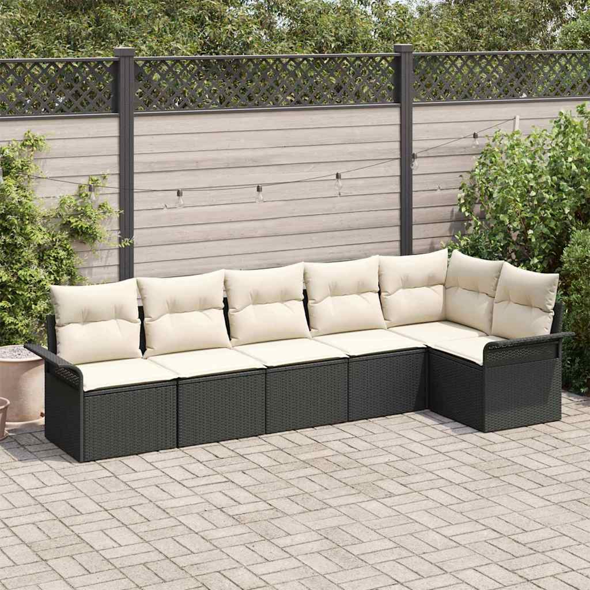 Dunkelgraues Outdoor-Ecksofa mit cremefarbenen Kissen auf einer Ziegelstein-Terrasse. Holzzaun und Grün im Hintergrund.