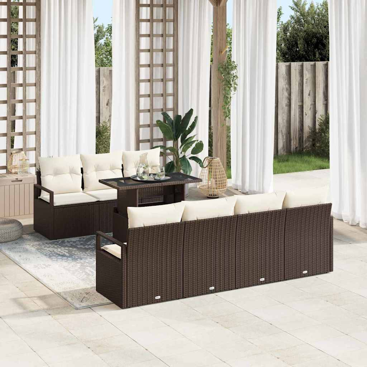 Garten-Terrassenset mit braunen Korbsesseln, cremefarbenen Kissen und einem schwarzen Tisch. Weiße Vorhänge und ein Holzgitter im Hintergrund.