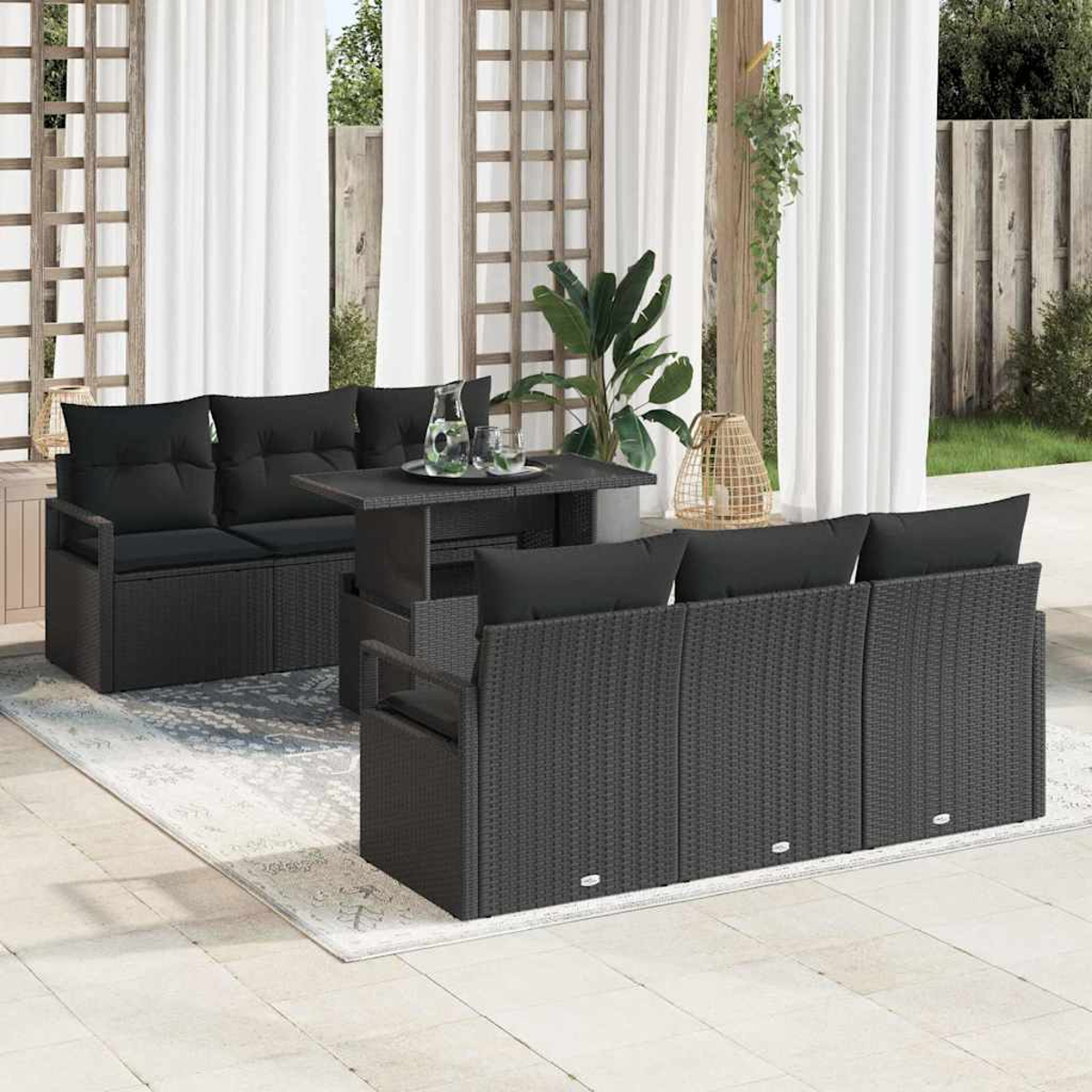 Terrassen-Set mit schwarzen Korbmöbeln, Tisch und Kissen. Weiße Vorhänge und ein Holzgitter im Hintergrund.