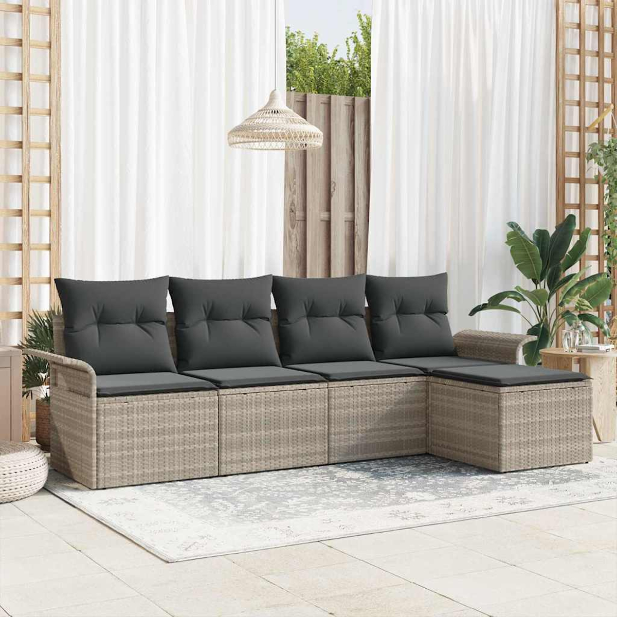 Ein Outdoor-Rattansofa mit grauen Kissen. Weiße Vorhänge und eine gewebte Lampe hängen darüber. Pflanzen und ein Teppich ergänzen die Szene.