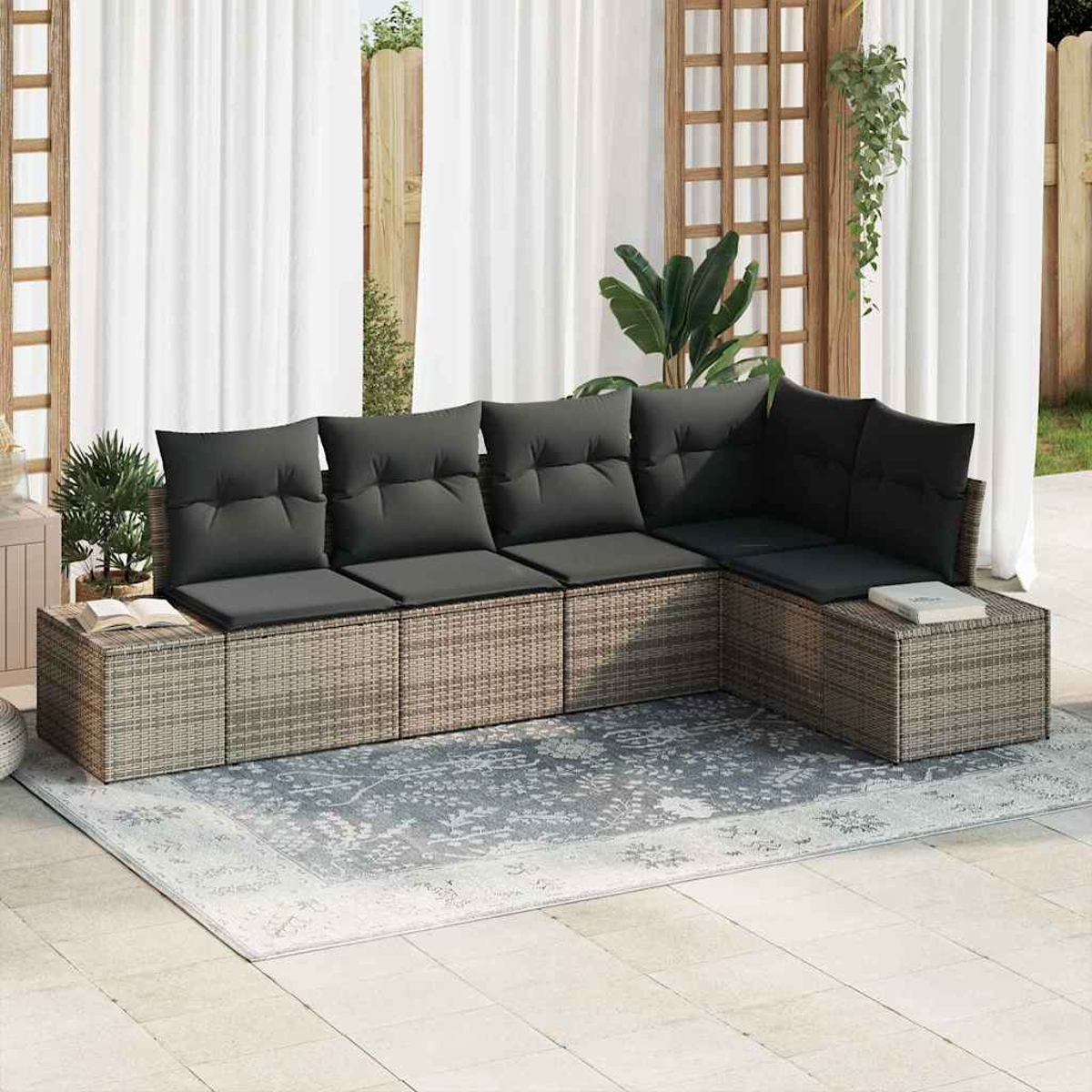 Ein Ecksofa im Freien mit grauen Kissen steht auf einem gemusterten Teppich. Weiße Vorhänge und Holzgitter befinden sich hinter dem Sofa.