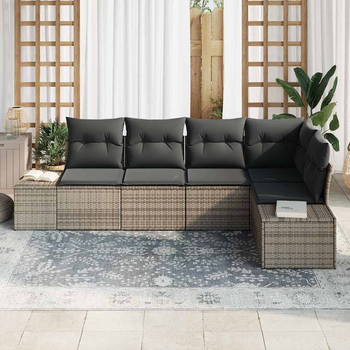 Outdoor-Ecksofa mit grauen Kissen auf einem gemusterten Teppich. Weiße Vorhänge und Holzgitter im Hintergrund.