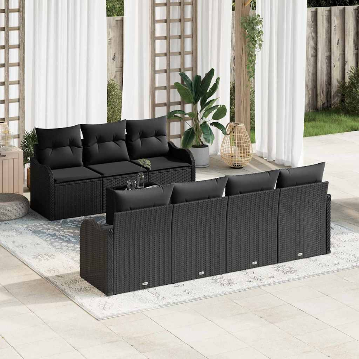 Terrassenmöbel-Set im Freien mit schwarzen Korbmöbeln, schwarzen Kissen und einem Teppich. Enthält zwei Sofas und eine dekorative Laterne.