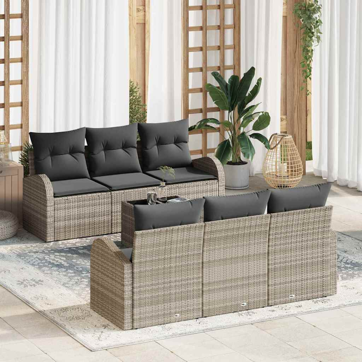 Terrassen-Set mit grauen Kissen. Ein Teppich, Pflanzen und eine dekorative Laterne vervollständigen die Szene. Weiße Vorhänge und Holzrahmen sind im Hintergrund.