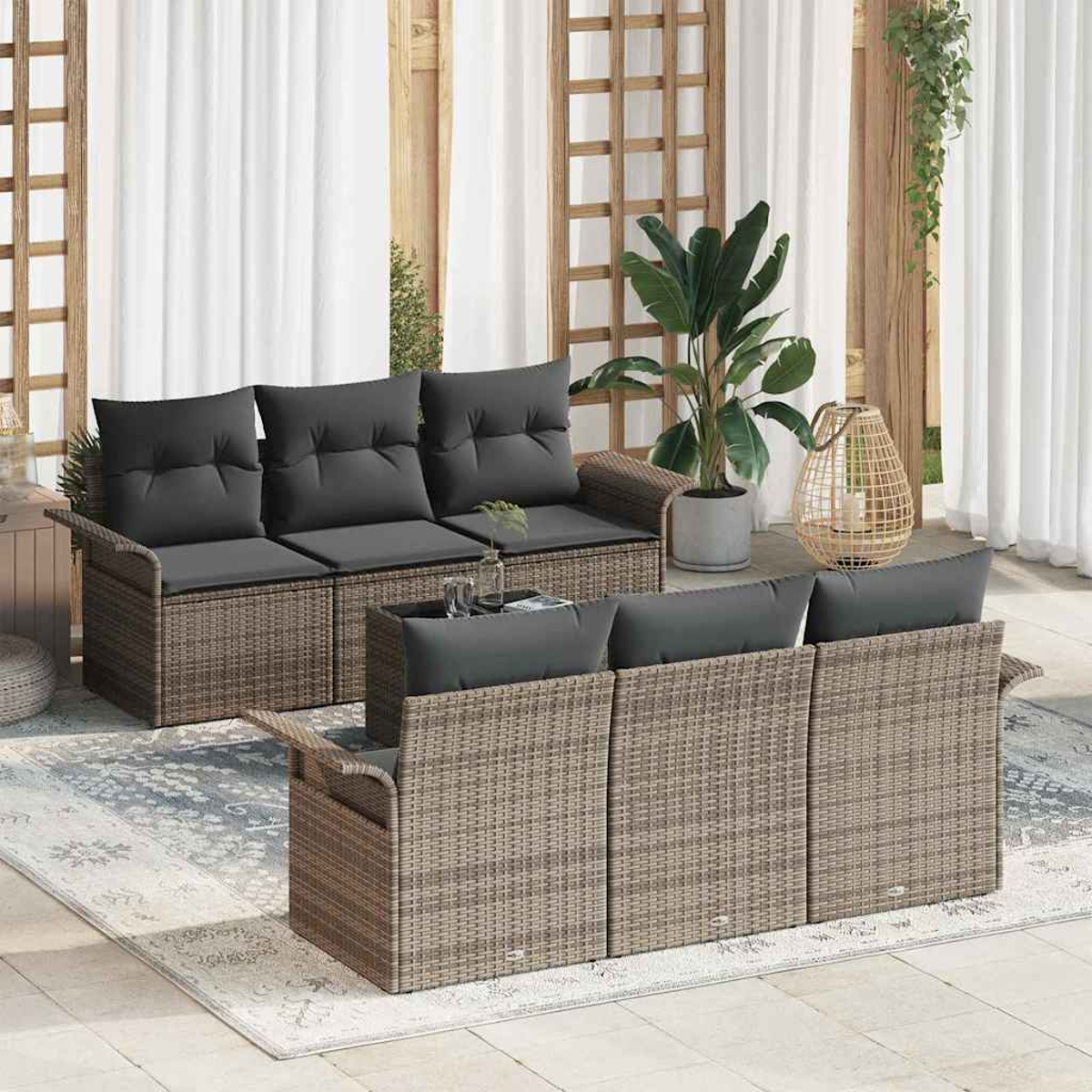 Szene im Freien mit zwei Rattansofas mit grauen Kissen. Eine große Pflanze in einem Topf, eine Laterne und ein gemusterter Teppich sind ebenfalls zu sehen.