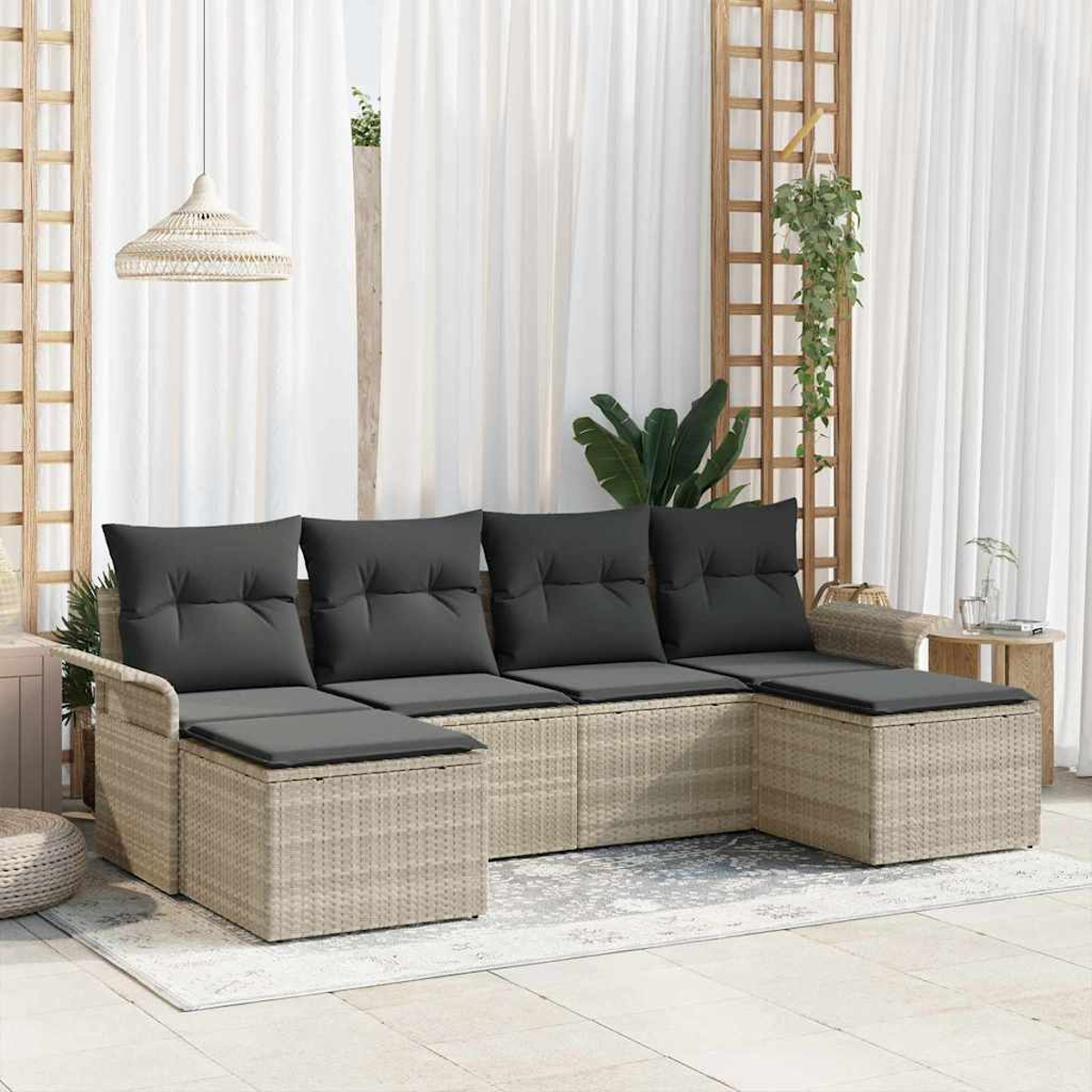 Geflochtenes Ecksofa mit dunkelgrauen Kissen. Dahinter weiße Vorhänge, Holzgitter mit Pflanzen und eine gewebte Lampe.