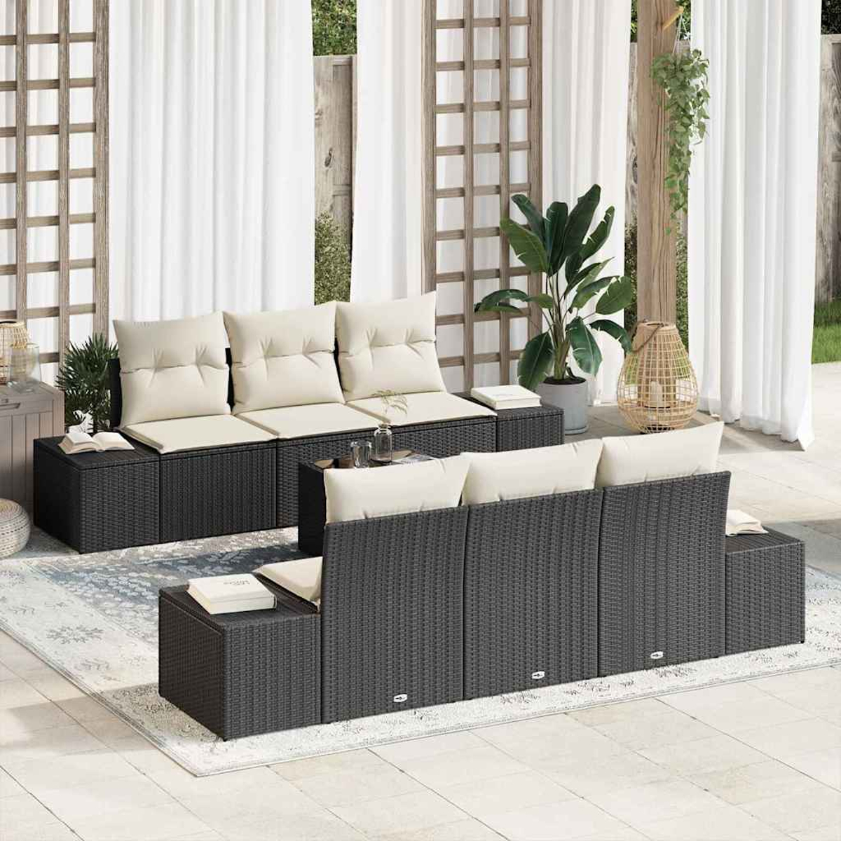 Juego de asientos al aire libre: sofás de mimbre negro con cojines crema. Cortinas blancas, plantas y una linterna decorativa en el fondo.