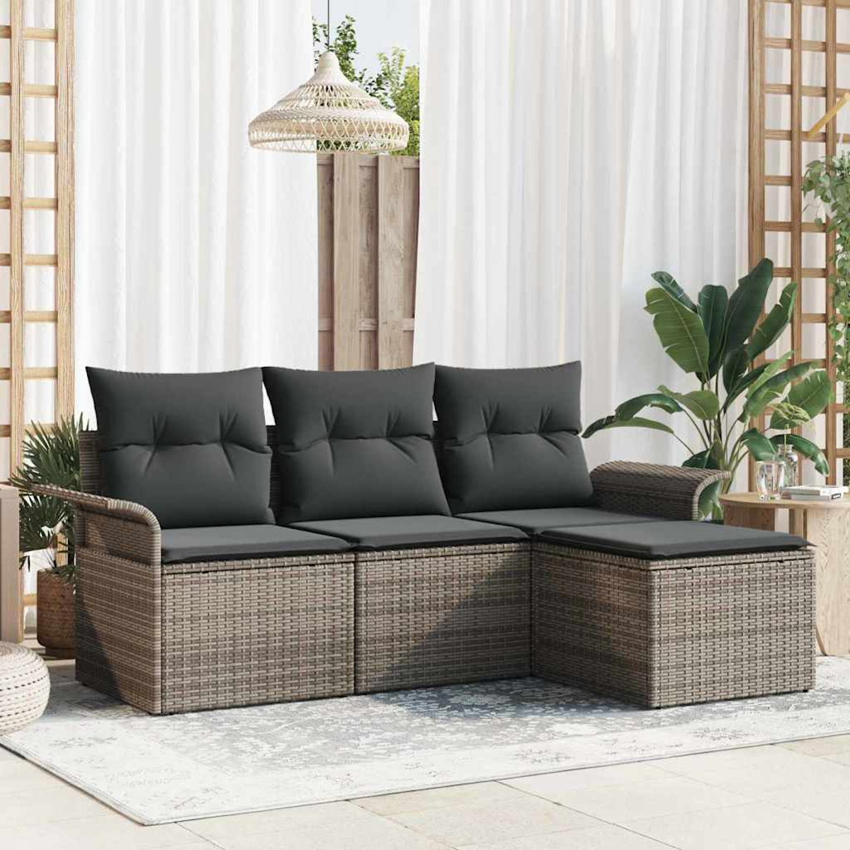 Outdoor-Ecksofa mit grauen Kissen. Der gewebte braune Rahmen steht auf einem hellen Teppich. Weiße Vorhänge und Pflanzen im Hintergrund.