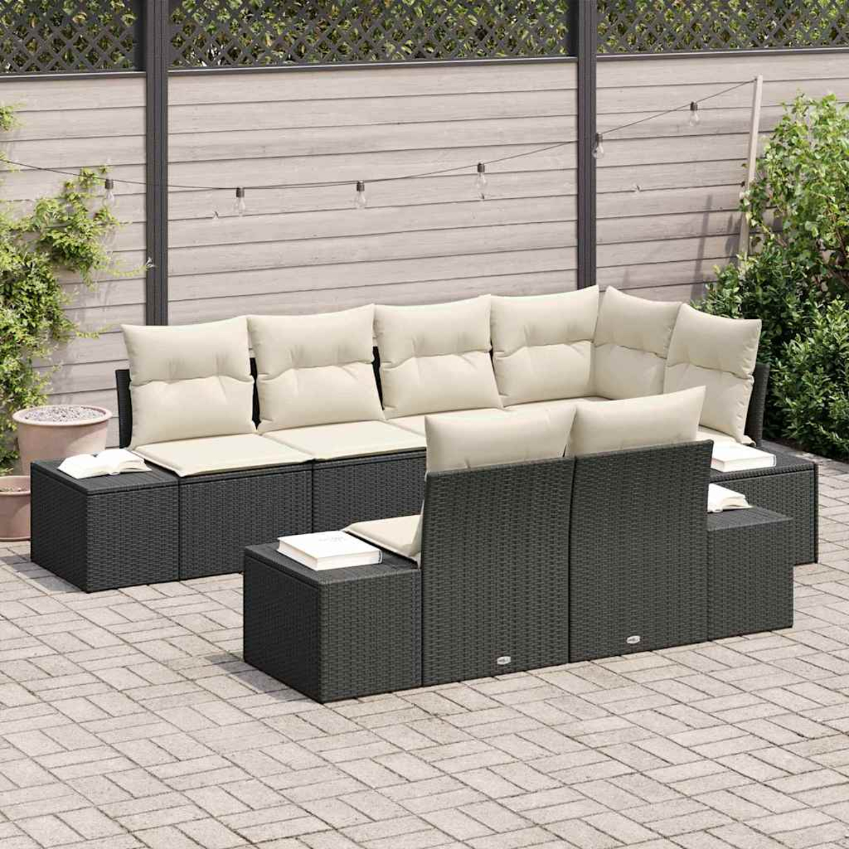 Gartenmöbel-Set, dunkelgraues Geflecht mit cremefarbenen Kissen. Bücher auf Beistelltischen. Graue Ziegelterrasse mit Zaun und Pflanzen.