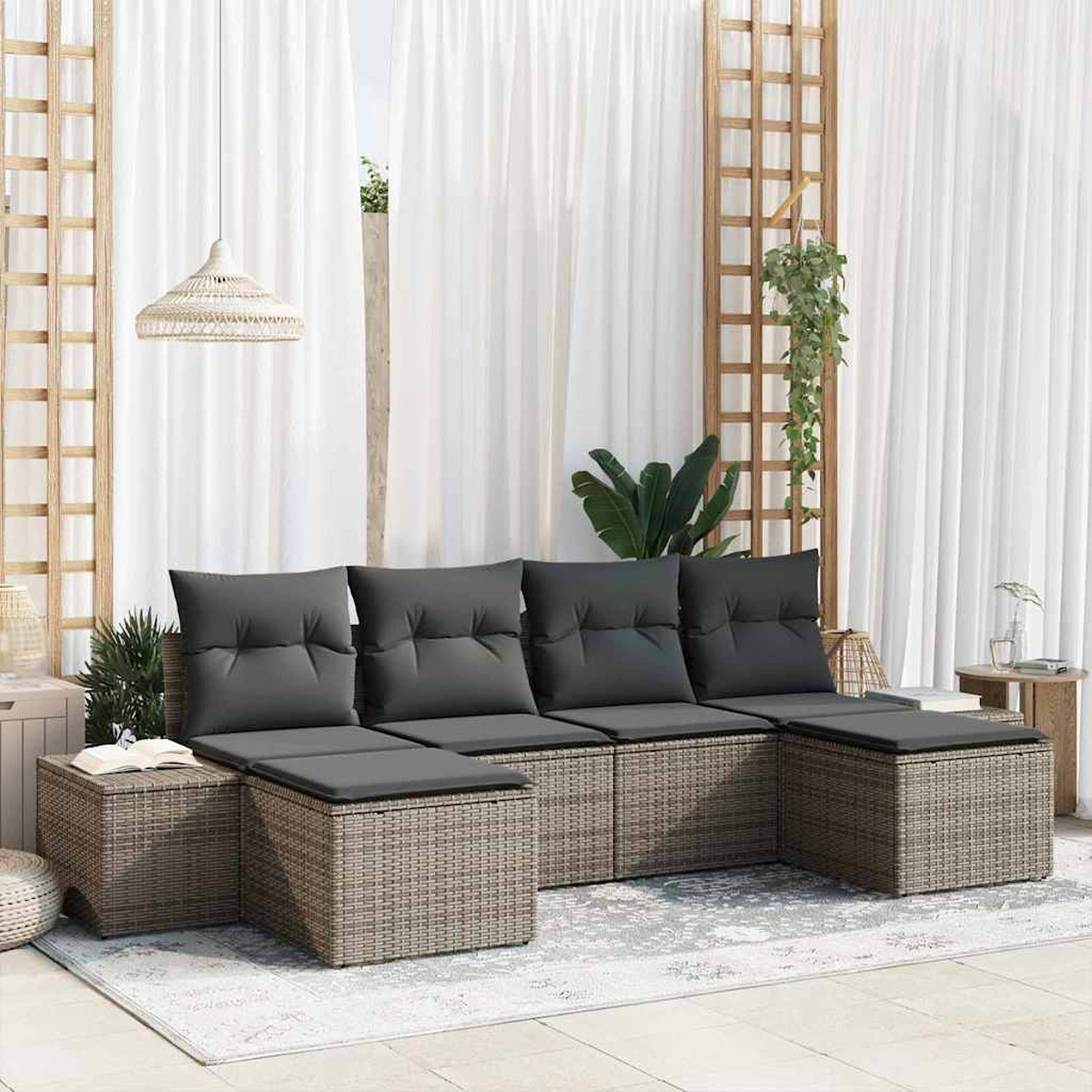 Eine Sitzgruppe im Freien mit grauen Kissen. Sie umfasst ein Sofa, Ottomanen und einen Teppich. Weiße Vorhänge und ein Holzgitter sind im Hintergrund.