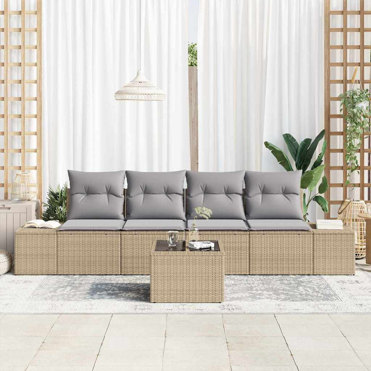 Asientos al aire libre con cojines grises, mesa de centro y cortinas blancas. Plantas y una lámpara tejida en el fondo.