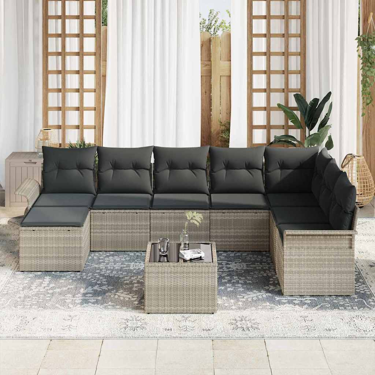 Outdoor-Ecksofa mit grauen Kissen. Quadratischer Couchtisch davor. Weiße Vorhänge und Außendekoration im Hintergrund.