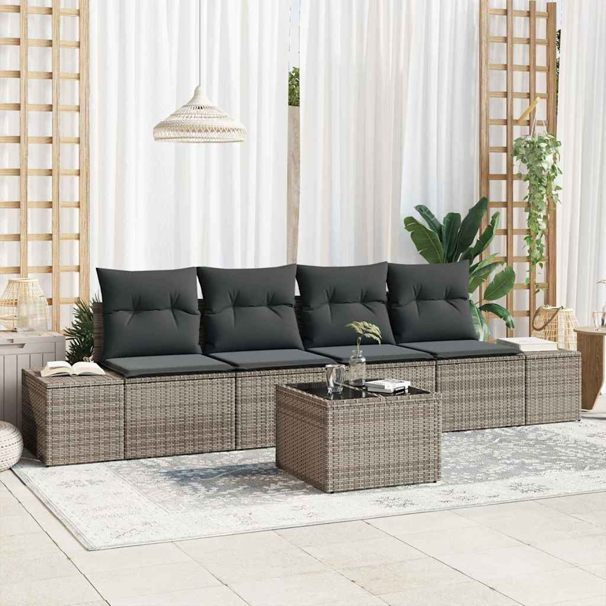 Outdoor-Sitzbereich mit grauen Kissen, Couchtisch und weißen Vorhängen. Pflanzen und eine gewebte Lampe sind ebenfalls sichtbar.