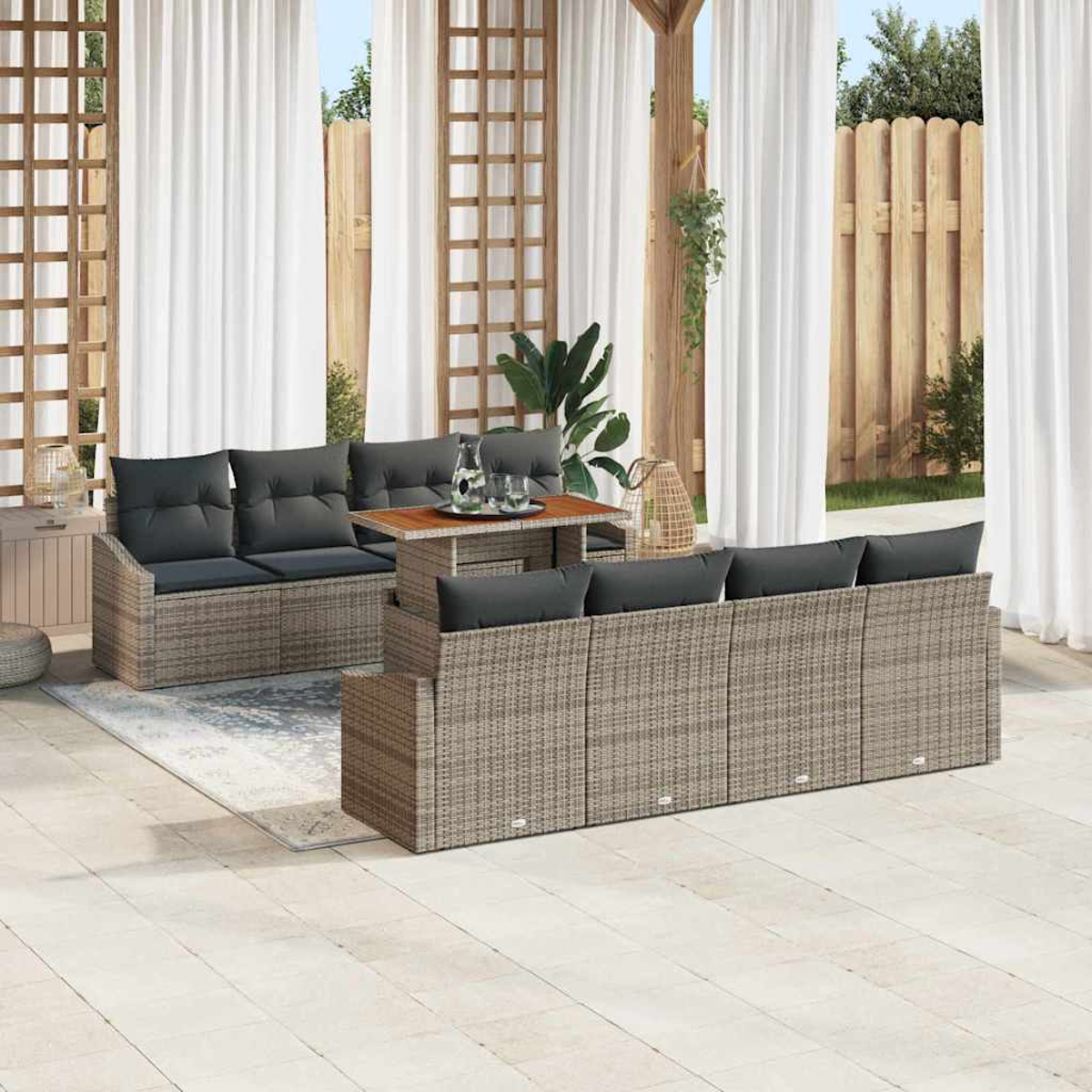Gartenmöbel-Set auf der Terrasse. Enthält Korbsessel mit grauen Kissen, einen Tisch und weiße Vorhänge im Hintergrund.