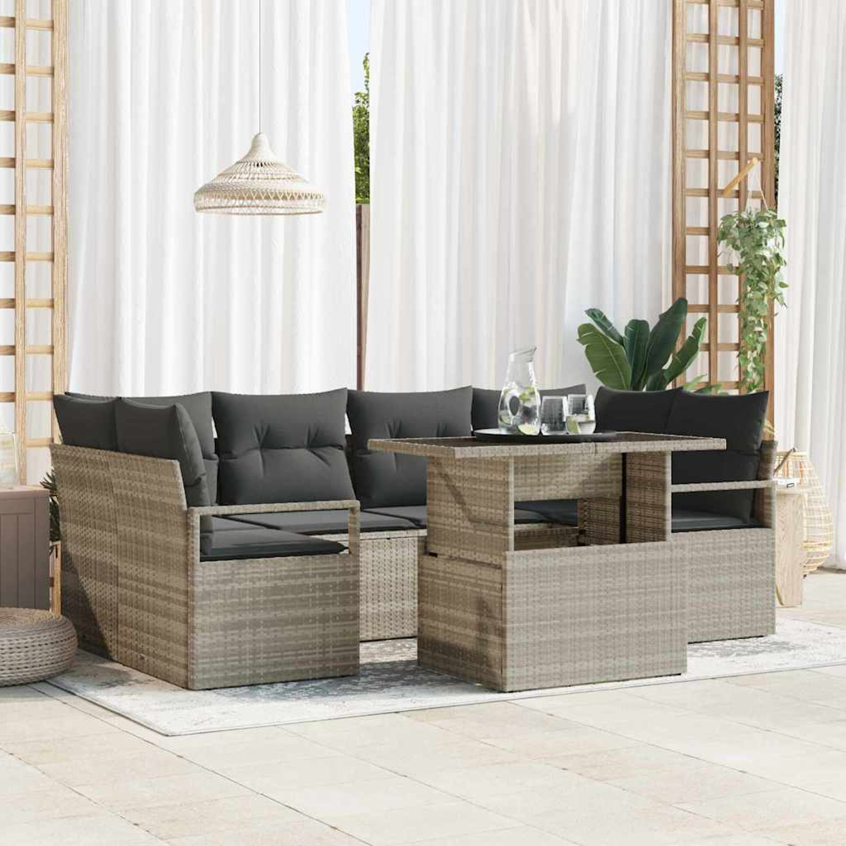 Gartenmöbel-Set aus Korbgeflecht mit grauen Kissen. Enthält einen Tisch, zwei Sofas und eine Hängelampe. Hintergrund mit weißen Vorhängen.