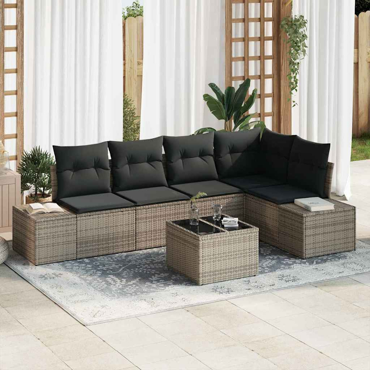 Outdoor-Ecksofa mit schwarzen Kissen, Couchtisch, Teppich und Vorhängen. Pflanzen und Holzgitter im Hintergrund.