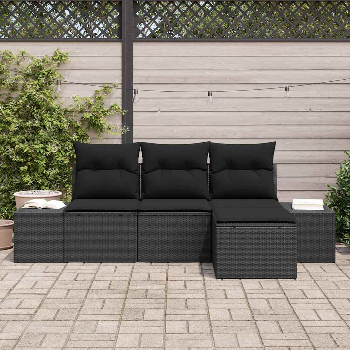 Schwarzes Outdoor-Korbmöbel mit Kissen. Die Terrasse hat einen Holzzaun, Pflanzen und Lichterketten.
