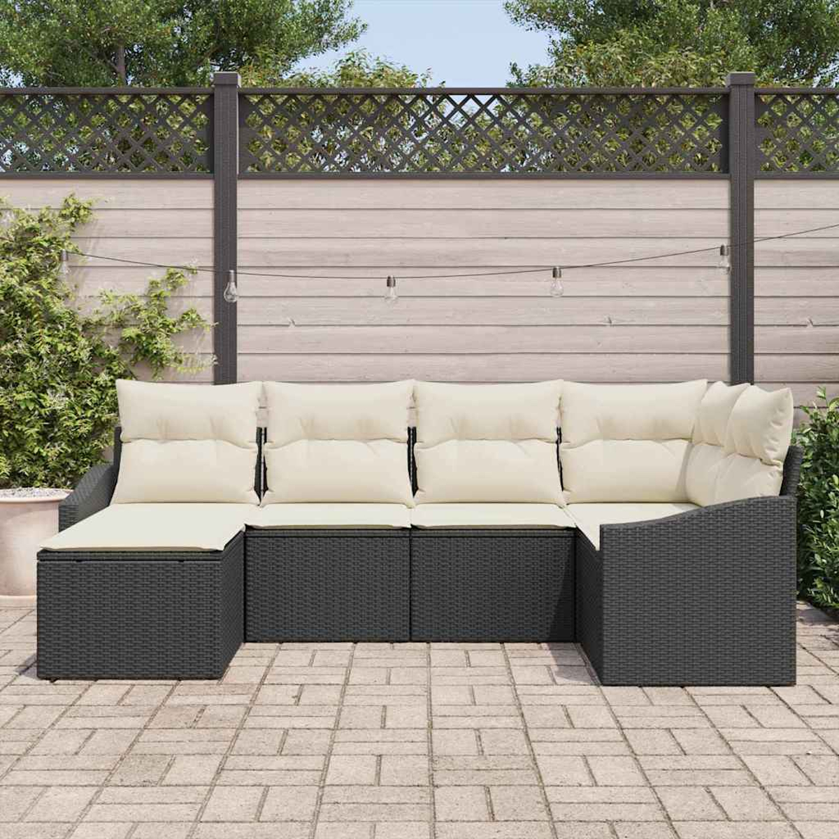 Outdoor-Ecksofa mit cremefarbenen Kissen, dunkelgrauem gewebtem Rahmen, auf einer Ziegelsteinterrasse. Im Hintergrund ein Holzzaun.