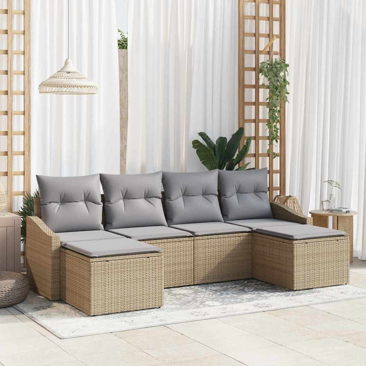 Ein Rattansofa für den Außenbereich mit grauen Kissen steht auf einem Teppich. Weiße Vorhänge, ein Holzgitter und Pflanzen sind im Hintergrund.