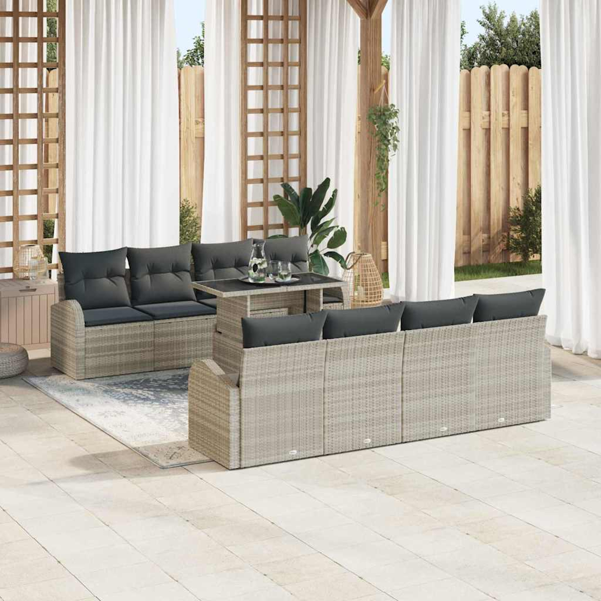 Garten-Terrassenset mit grauen Kissen. Enthält zwei Sofas, einen Tisch und einen Teppich, vor dem Hintergrund von Vorhängen und einem Holzzaun.